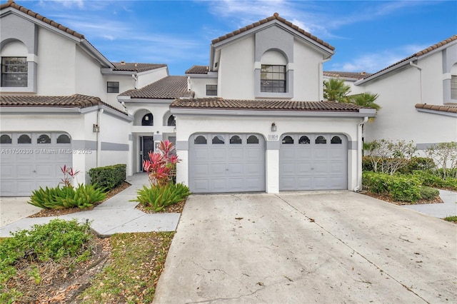 mediterranean / spanish home with a garage, concrete driveway, a tiled roof, and stucco siding