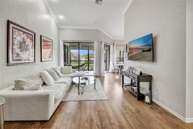 living area featuring crown molding, visible vents, a textured wall, wood finished floors, and baseboards