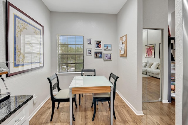 dining space featuring light wood-style flooring and baseboards