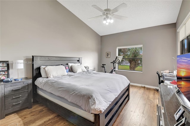 bedroom with a textured ceiling, baseboards, vaulted ceiling, and wood finished floors