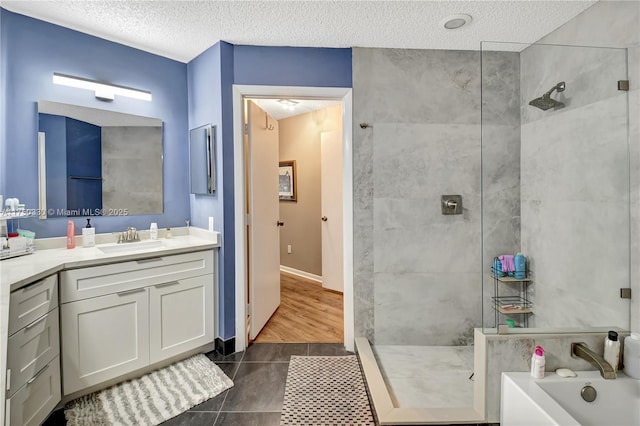 full bath featuring a garden tub, vanity, a textured ceiling, walk in shower, and tile patterned floors