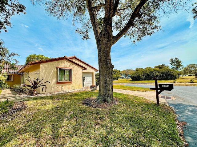 view of home's exterior with an attached garage, a lawn, stucco siding, and concrete driveway
