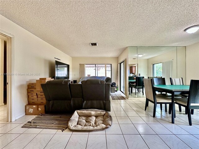living area featuring visible vents, a textured ceiling, and light tile patterned flooring