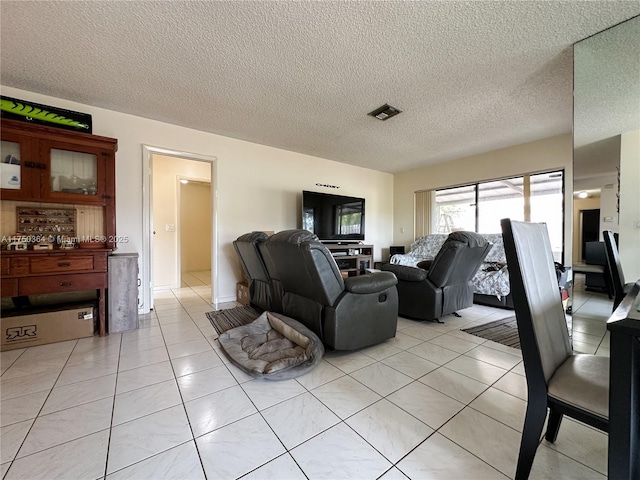 living room featuring light tile patterned flooring, visible vents, and a textured ceiling
