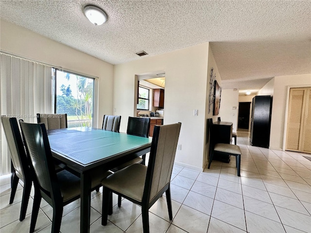 dining room featuring visible vents, light tile patterned floors, and a textured ceiling