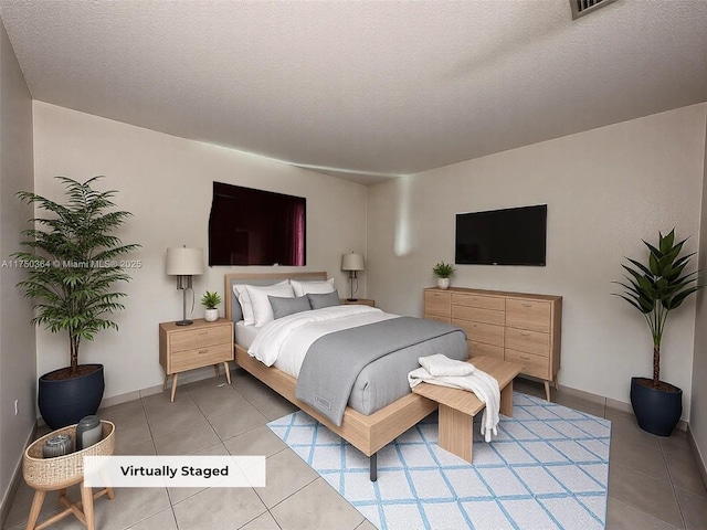 bedroom featuring baseboards, light tile patterned floors, and a textured ceiling