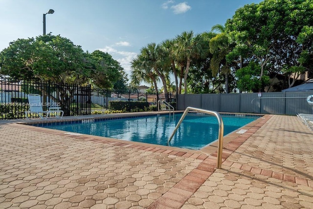 community pool with fence and a patio area
