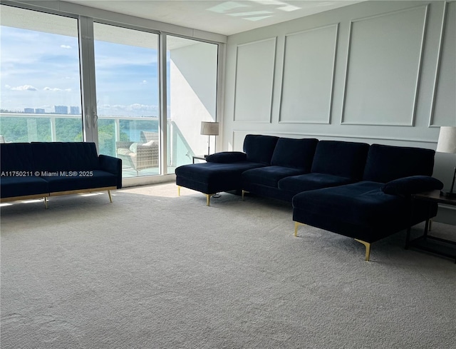 living area featuring expansive windows, light colored carpet, a decorative wall, and a city view