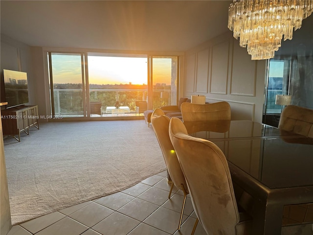 dining area with light colored carpet, a decorative wall, a notable chandelier, and light tile patterned flooring