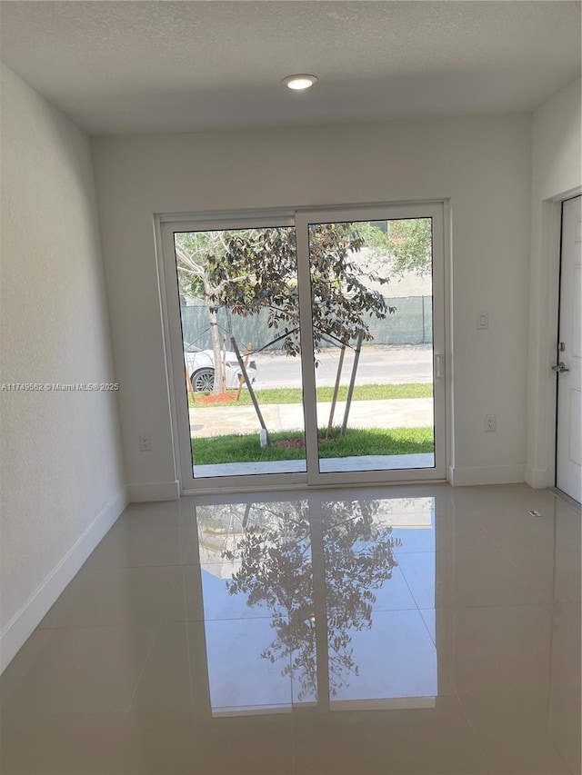 doorway to outside featuring recessed lighting, a textured ceiling, baseboards, and tile patterned floors