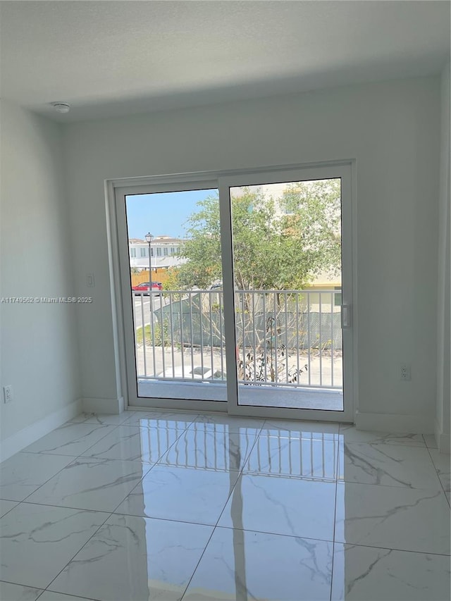 spare room featuring marble finish floor and baseboards