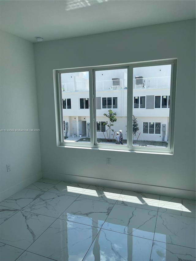 spare room featuring marble finish floor and baseboards