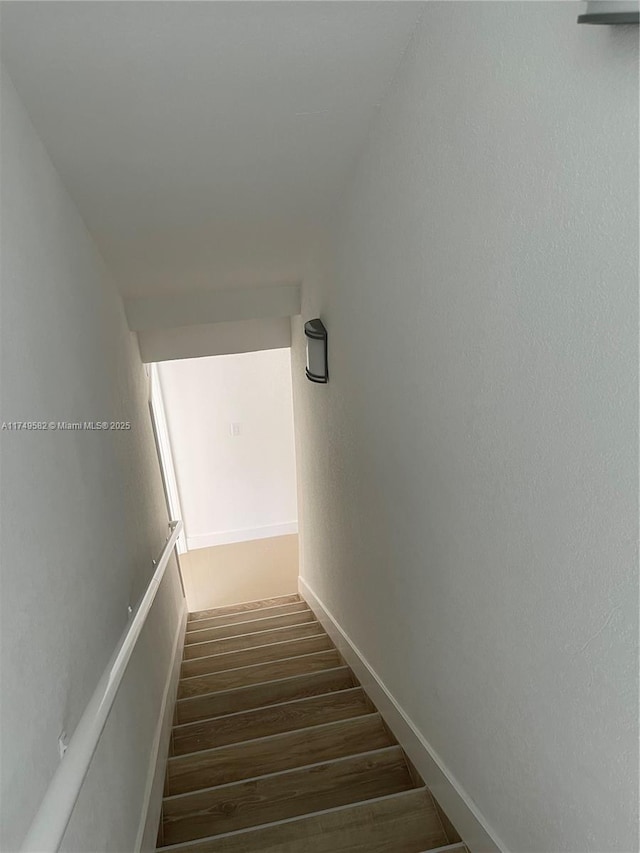 stairway with wood finished floors and baseboards