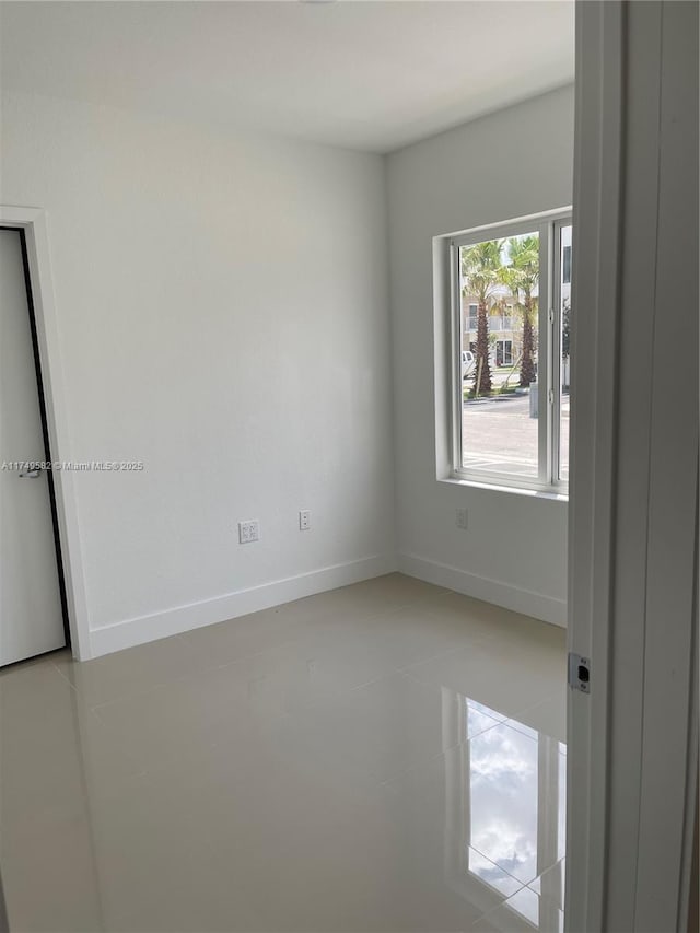 empty room with baseboards and light tile patterned floors