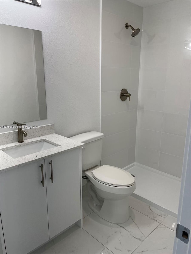 bathroom featuring toilet, marble finish floor, a shower stall, and vanity