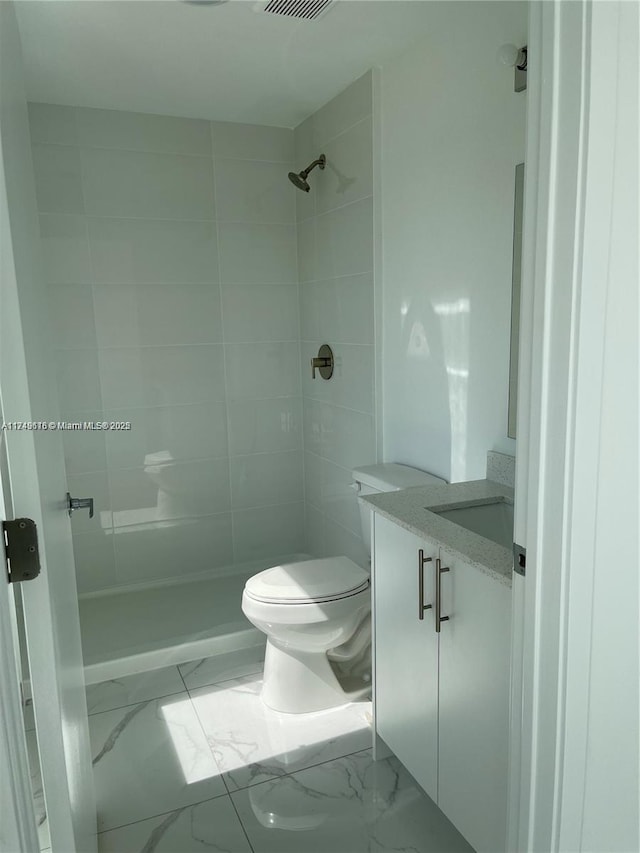 bathroom with toilet, marble finish floor, a stall shower, and vanity