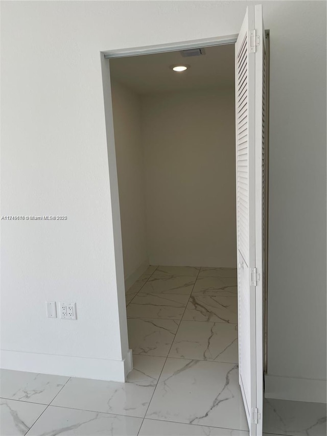 corridor featuring marble finish floor and baseboards