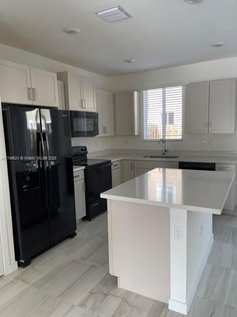 kitchen with visible vents, a center island, light countertops, black appliances, and a sink