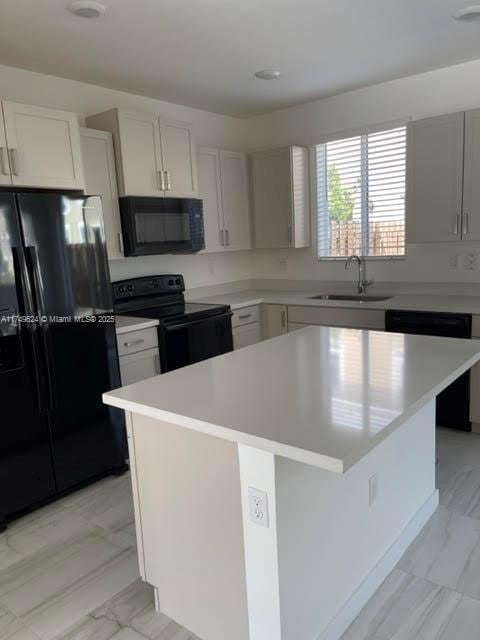 kitchen with black appliances, light countertops, a sink, and a center island