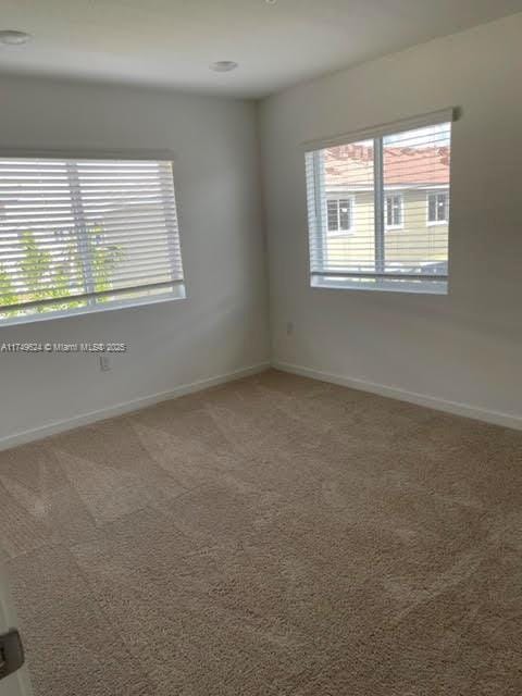 carpeted empty room featuring baseboards