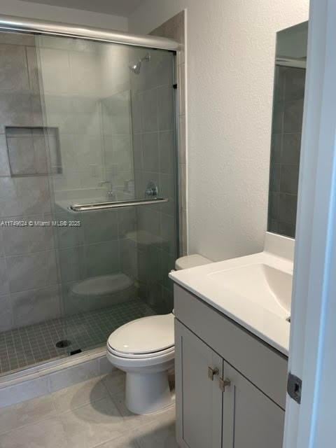 bathroom featuring a stall shower, vanity, and toilet