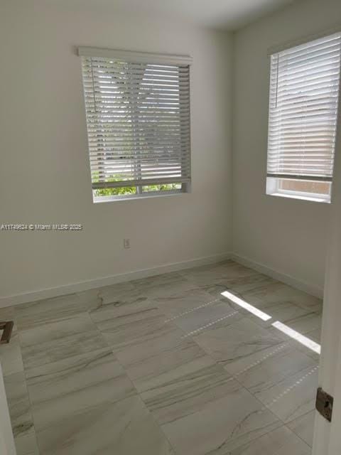 empty room with plenty of natural light and baseboards