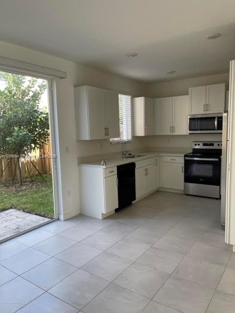 kitchen with stainless steel appliances, plenty of natural light, light countertops, and white cabinetry