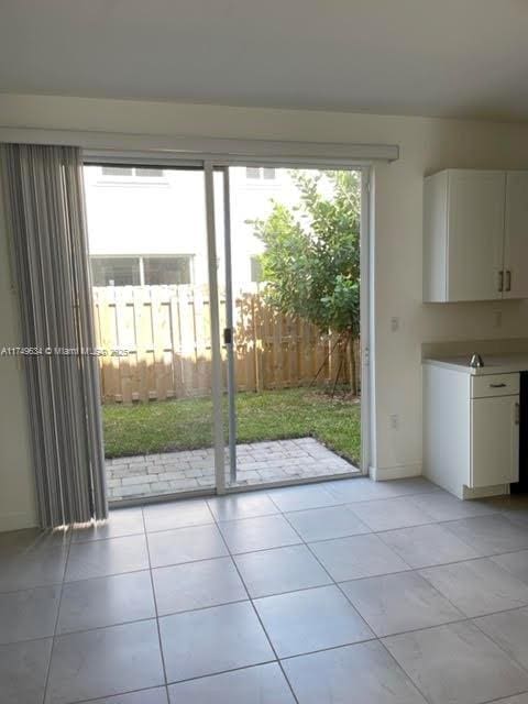 doorway featuring light tile patterned floors, plenty of natural light, and baseboards