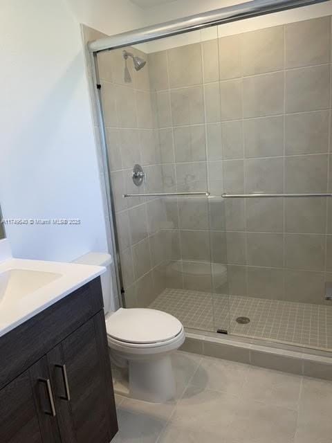 full bath with a stall shower, vanity, toilet, and tile patterned floors