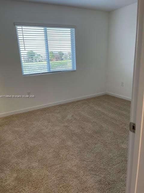 carpeted empty room featuring baseboards