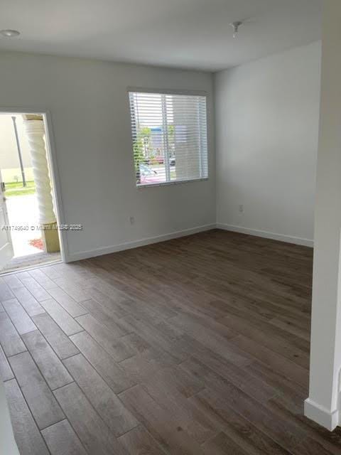 unfurnished room with dark wood finished floors and baseboards