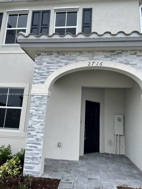 property entrance with stone siding and stucco siding