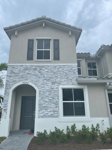 view of front of property featuring stone siding and stucco siding