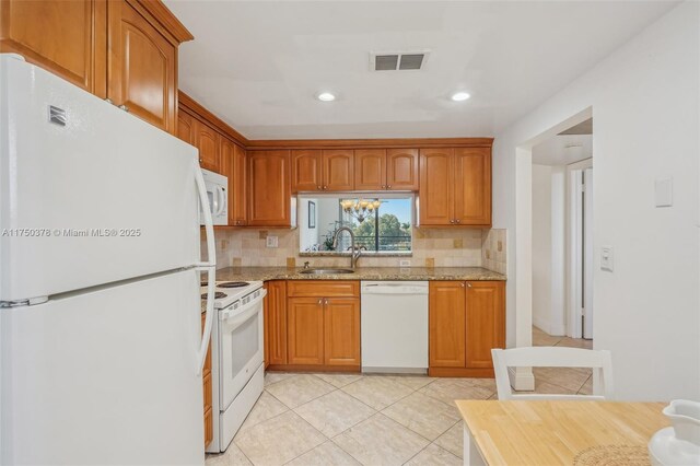kitchen featuring visible vents, tasteful backsplash, light stone countertops, a sink, and white appliances