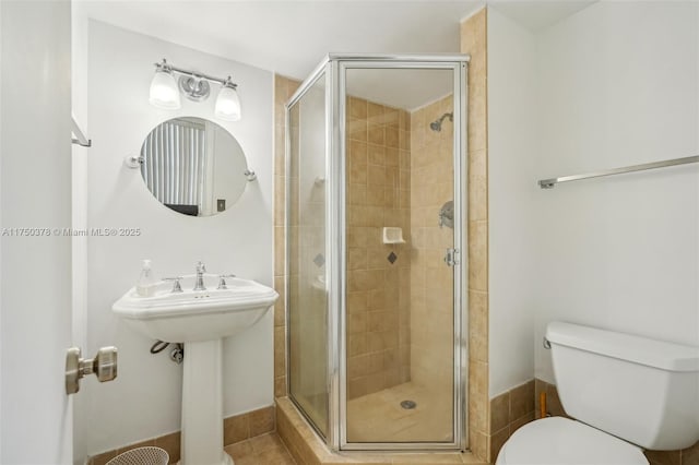 full bathroom featuring a stall shower, a sink, and toilet