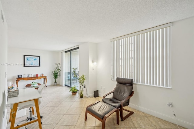 living area with a textured ceiling, a wall of windows, light tile patterned flooring, and baseboards