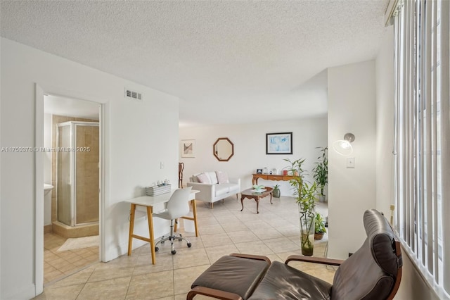 living area featuring light tile patterned floors, visible vents, a wealth of natural light, and a textured ceiling