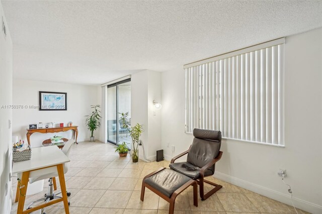 living area featuring a textured ceiling, baseboards, and light tile patterned flooring
