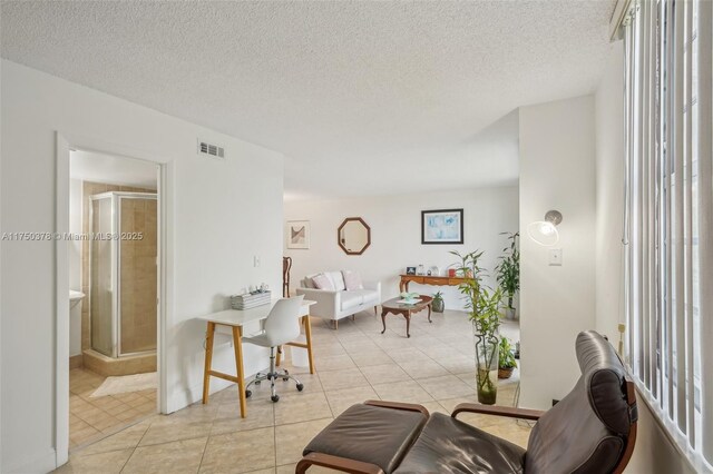 living area with a textured ceiling, light tile patterned flooring, and visible vents