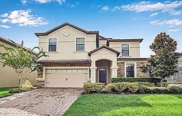 view of front facade featuring a garage, a front yard, decorative driveway, and stucco siding