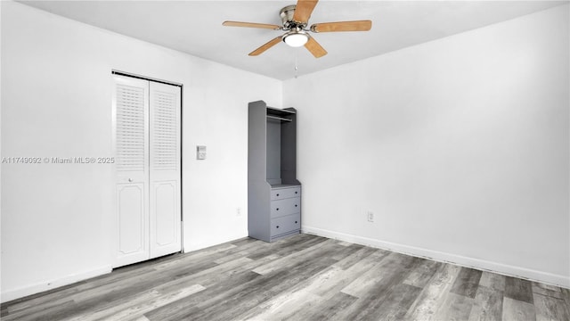 unfurnished bedroom featuring ceiling fan, a closet, baseboards, and light wood-style floors