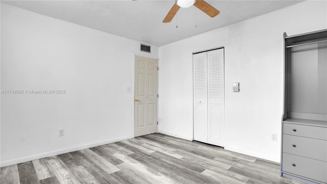 unfurnished bedroom featuring baseboards, ceiling fan, visible vents, and light wood-style floors