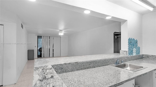 kitchen with ceiling fan, a peninsula, a sink, visible vents, and light countertops