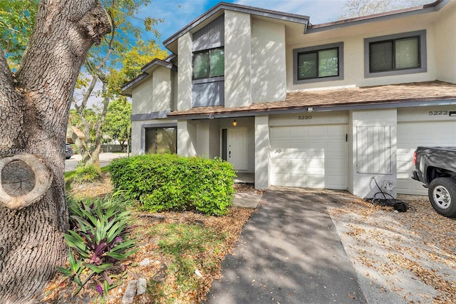 view of property with a garage, driveway, and stucco siding