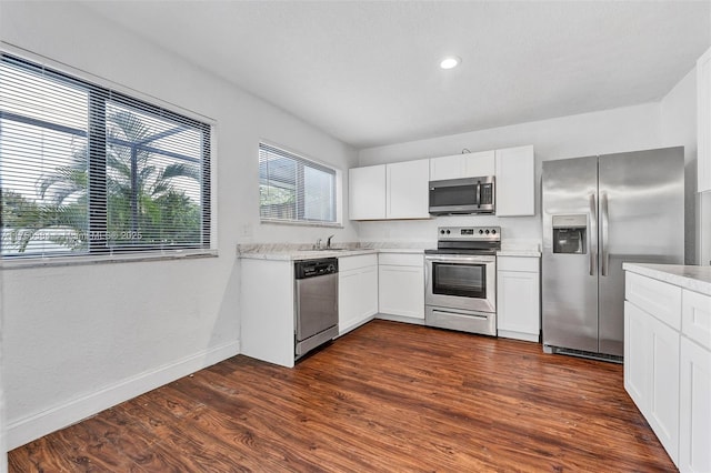 kitchen with white cabinets, dark wood-style flooring, stainless steel appliances, and light countertops