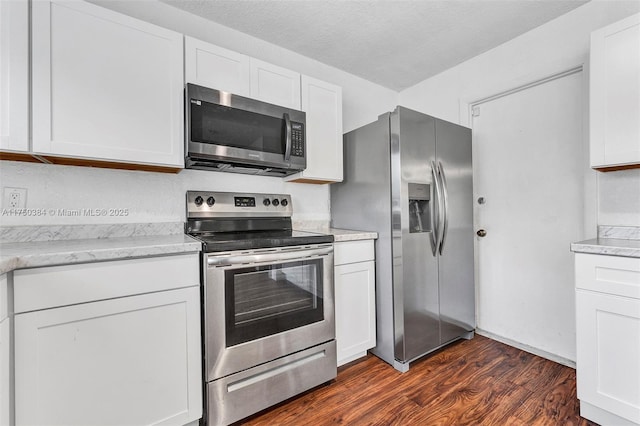 kitchen featuring white cabinets, light stone counters, appliances with stainless steel finishes, dark wood-style flooring, and a textured ceiling