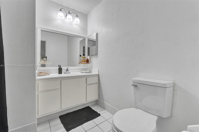 half bathroom featuring toilet, a textured wall, tile patterned flooring, and vanity