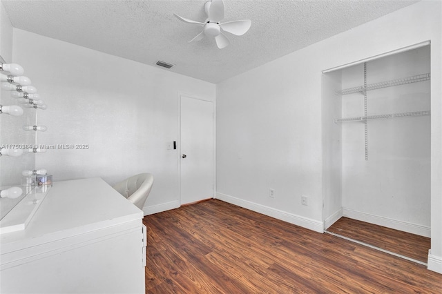 unfurnished office featuring visible vents, dark wood-type flooring, ceiling fan, a textured ceiling, and baseboards