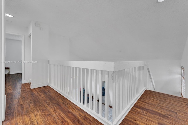 hallway featuring dark wood-style floors, lofted ceiling, and baseboards