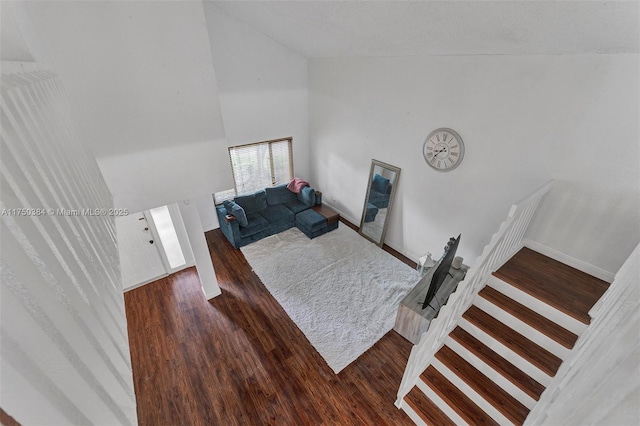 living room with dark wood-style floors, high vaulted ceiling, stairway, and baseboards